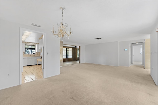 carpeted empty room featuring an inviting chandelier