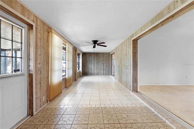 corridor featuring light colored carpet and wood walls