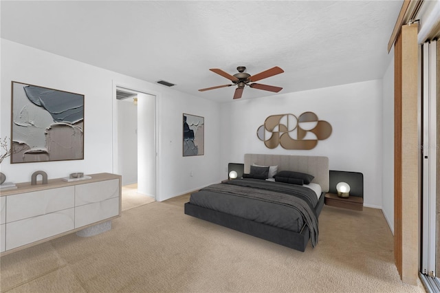 bedroom featuring ceiling fan, light colored carpet, and a textured ceiling