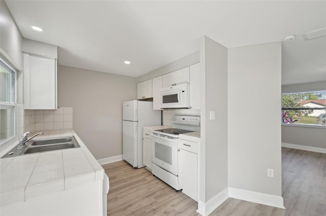 kitchen with sink, light hardwood / wood-style flooring, tile counters, white appliances, and white cabinets