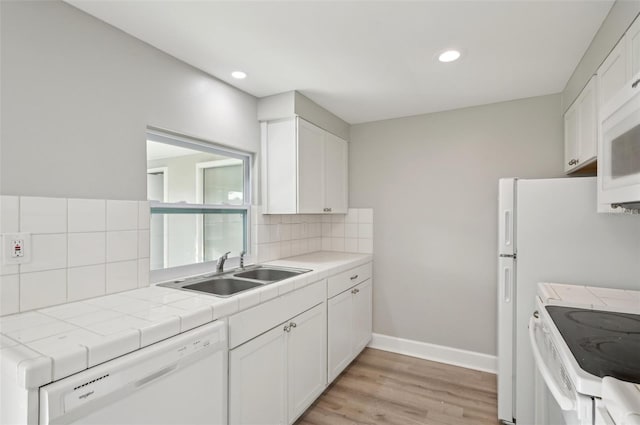 kitchen featuring tile countertops, tasteful backsplash, sink, white cabinets, and white appliances