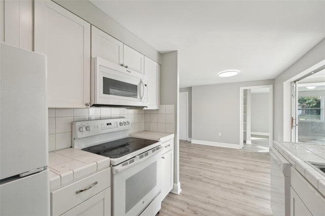 kitchen featuring white cabinetry, white appliances, tile counters, and decorative backsplash