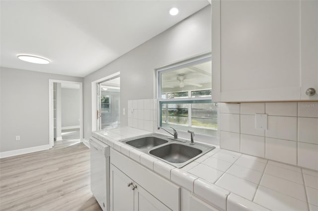 kitchen featuring tile countertops, dishwasher, sink, and white cabinets