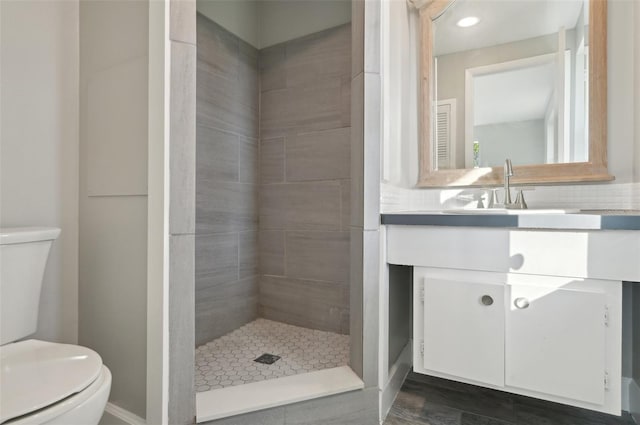 bathroom with vanity, tiled shower, and toilet