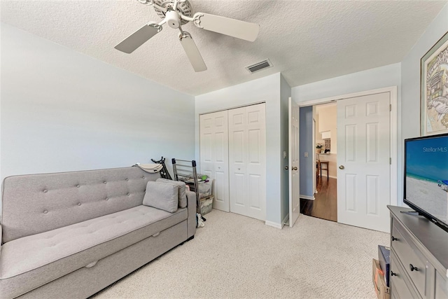 living area featuring light colored carpet, a textured ceiling, and ceiling fan