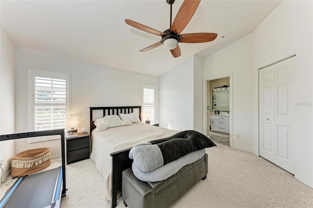 bedroom with ceiling fan, ensuite bathroom, vaulted ceiling, and light carpet