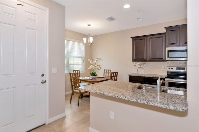 kitchen with appliances with stainless steel finishes, sink, decorative backsplash, light stone counters, and dark brown cabinets