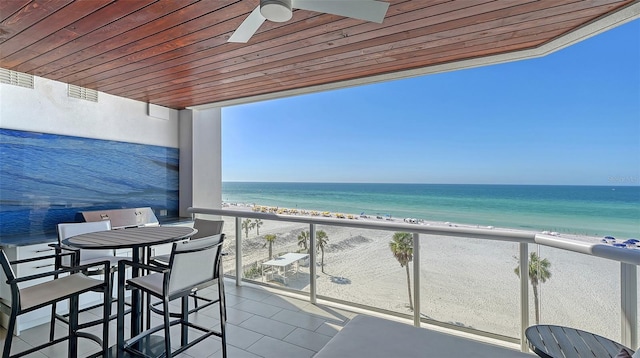 balcony with a water view, ceiling fan, and a view of the beach