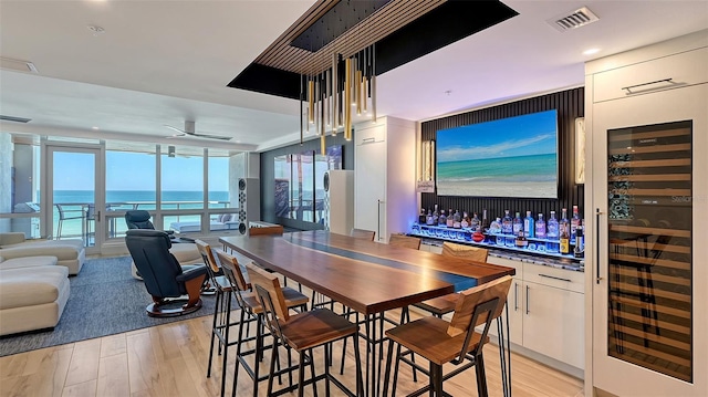 bar with light hardwood / wood-style flooring, ceiling fan, a water view, wine cooler, and white cabinets