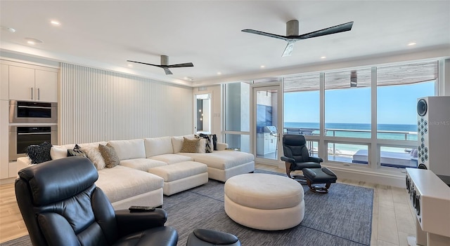 living room featuring light hardwood / wood-style flooring, ceiling fan, and a water view