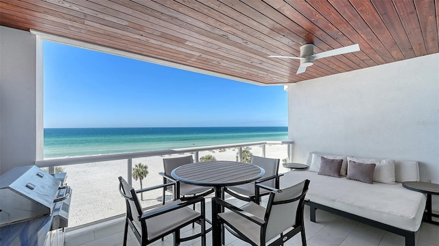 balcony with a water view, ceiling fan, and a beach view