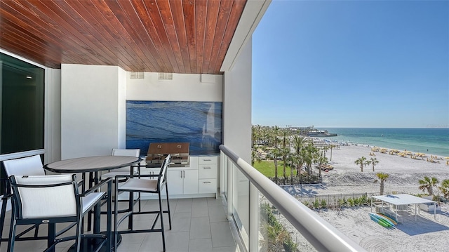 balcony with a water view, a beach view, and a grill