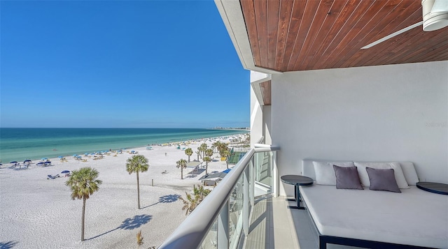 balcony with a water view, a beach view, and ceiling fan