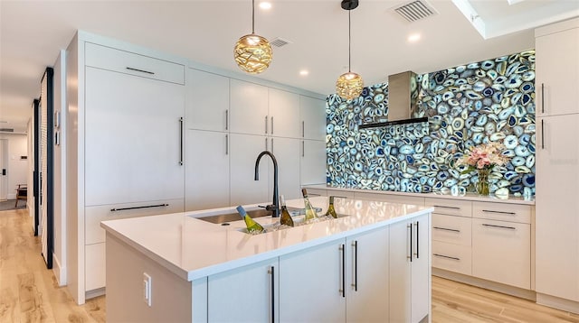 kitchen featuring hanging light fixtures, white cabinetry, sink, and a center island with sink