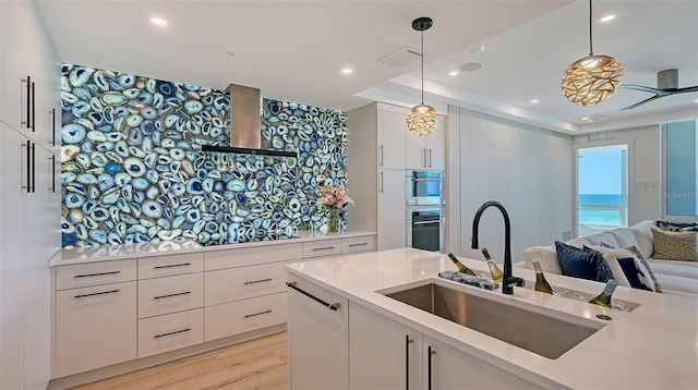 kitchen with sink, wall chimney range hood, white cabinets, and black electric cooktop