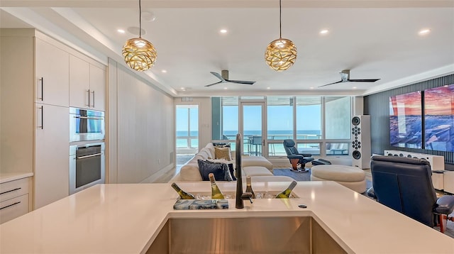 kitchen with pendant lighting, floor to ceiling windows, ceiling fan, and a water view