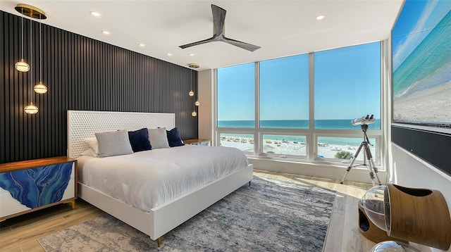 bedroom featuring a water view, ceiling fan, a beach view, and light hardwood / wood-style flooring