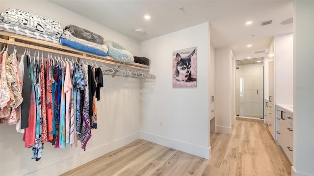 walk in closet with light hardwood / wood-style flooring