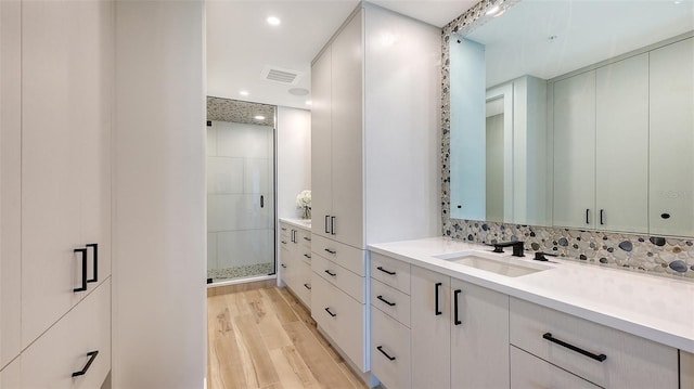 bathroom with tasteful backsplash, vanity, hardwood / wood-style flooring, and a shower with door