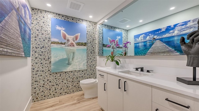 bathroom featuring wood-type flooring, vanity, and toilet