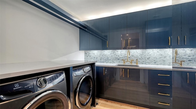 laundry room featuring cabinets, sink, washing machine and clothes dryer, and light wood-type flooring