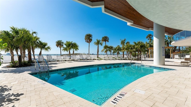 view of pool featuring a water view and a patio area