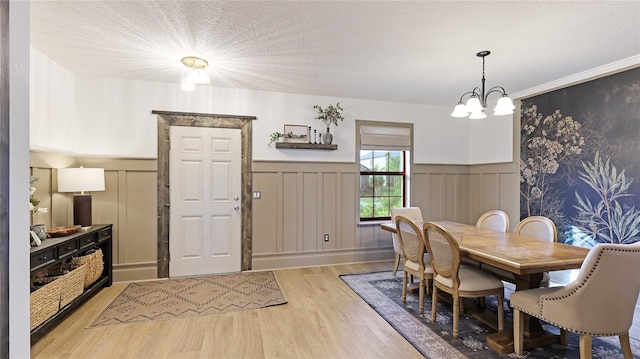 dining space featuring light hardwood / wood-style floors, an inviting chandelier, and a textured ceiling