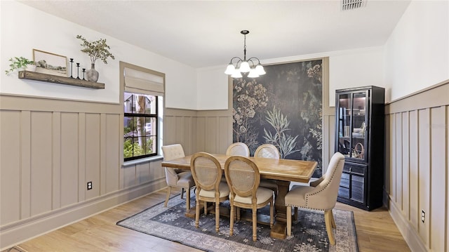 dining area with light wood-type flooring and an inviting chandelier