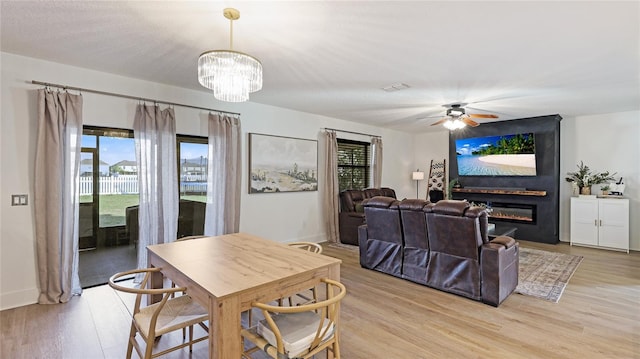 dining room with ceiling fan with notable chandelier and light hardwood / wood-style floors