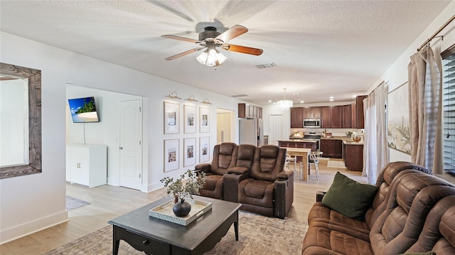 living room with light hardwood / wood-style flooring, ceiling fan, and a textured ceiling