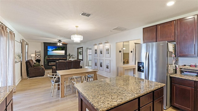 kitchen with light hardwood / wood-style flooring, light stone counters, a center island, and stainless steel refrigerator with ice dispenser