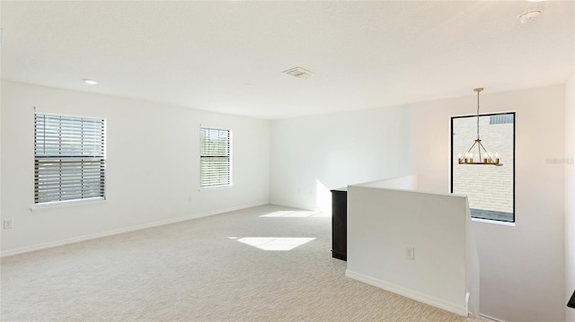 carpeted empty room featuring a notable chandelier