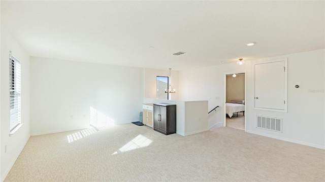 carpeted empty room with an inviting chandelier