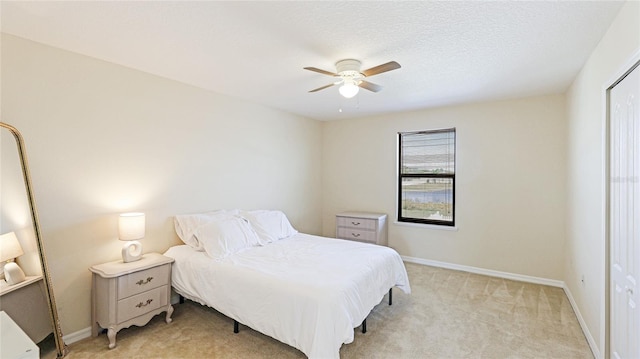 bedroom featuring ceiling fan, a textured ceiling, and light colored carpet