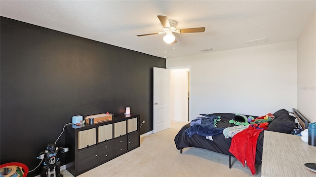 bedroom featuring ceiling fan, light carpet, and a textured ceiling