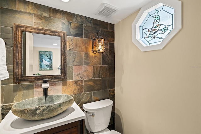 bathroom with vanity, toilet, tile walls, and backsplash