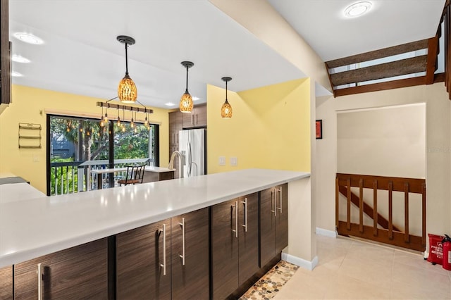 kitchen featuring stainless steel refrigerator with ice dispenser, dark brown cabinetry, light tile patterned flooring, and pendant lighting