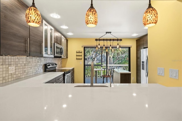 kitchen featuring tasteful backsplash, decorative light fixtures, dark brown cabinets, and stainless steel appliances