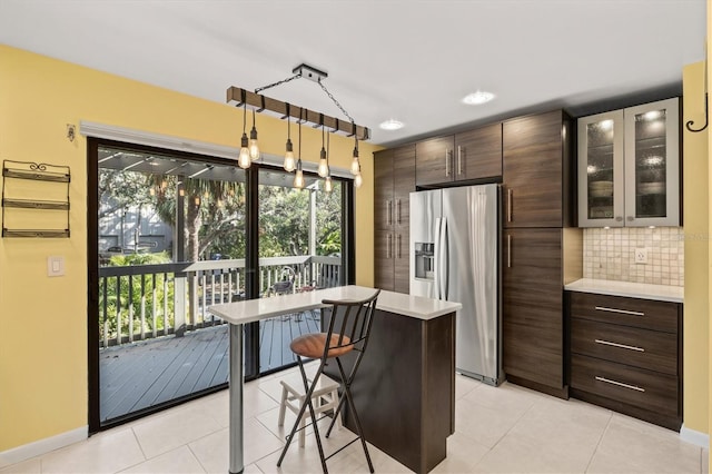 kitchen with pendant lighting, backsplash, a kitchen island, stainless steel refrigerator with ice dispenser, and a kitchen bar