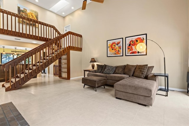 living room with a high ceiling, light tile patterned floors, and a skylight