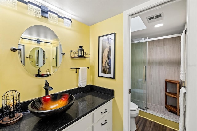 bathroom featuring walk in shower, wood-type flooring, vanity, and toilet