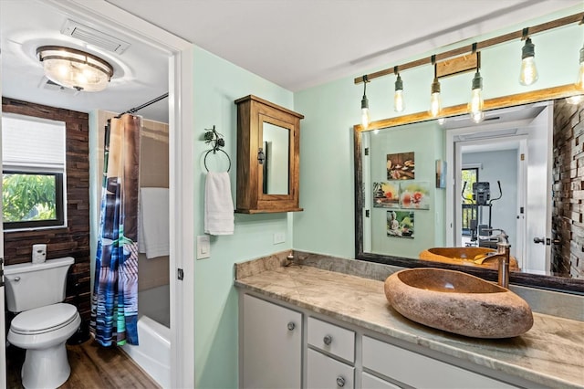 full bathroom featuring hardwood / wood-style flooring, vanity, shower / bath combination with curtain, and toilet