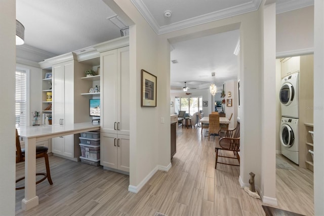 bar with white cabinetry, crown molding, built in desk, stacked washer / dryer, and light hardwood / wood-style floors