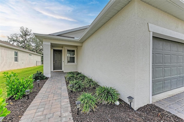 entrance to property featuring stucco siding and an attached garage