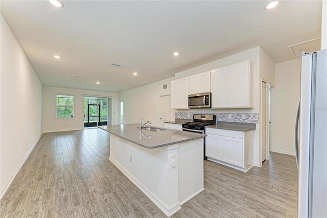 kitchen with visible vents, light wood-type flooring, stainless steel appliances, white cabinetry, and a sink