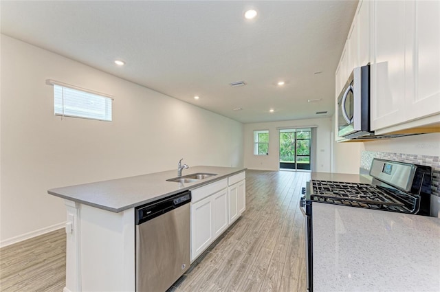 kitchen with a sink, light wood-style floors, appliances with stainless steel finishes, white cabinetry, and open floor plan