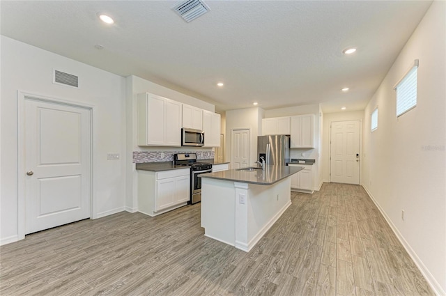 kitchen featuring dark countertops, visible vents, light wood finished floors, and stainless steel appliances