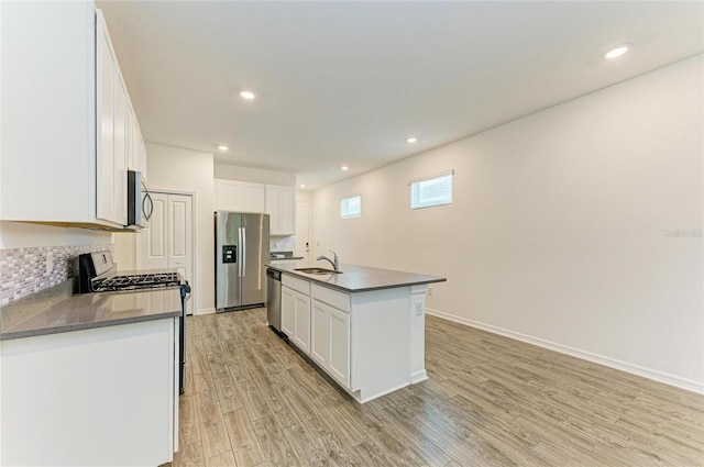 kitchen with a sink, dark countertops, light wood-type flooring, and stainless steel appliances