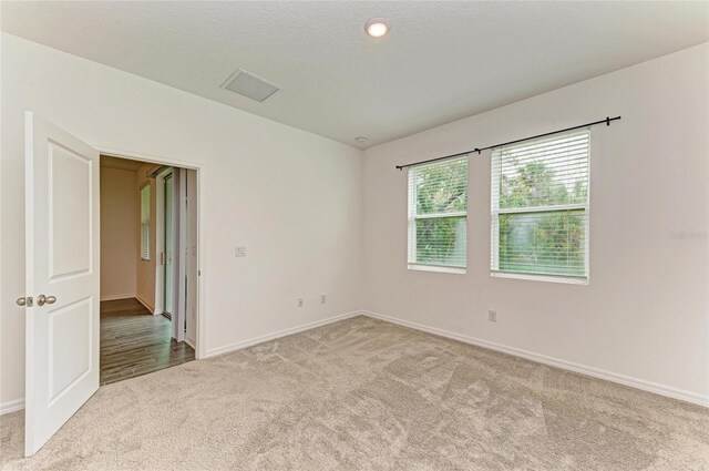 unfurnished room with visible vents, baseboards, a textured ceiling, and carpet flooring