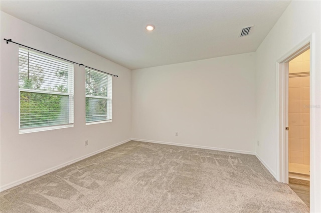 spare room with light carpet, visible vents, recessed lighting, and baseboards